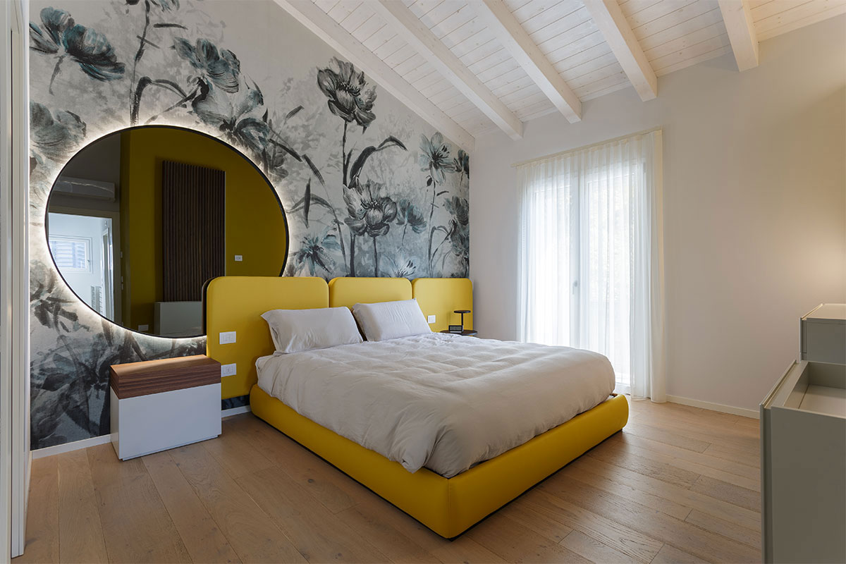 Arredamento camera da letto con letto in pelle gialla su misura, grande specchio rotondo e carta da parati floreale moderna
